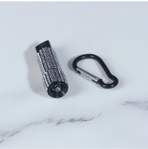 Macro view of a luxury rhinestone-encrusted mini LED flashlight with a black carabiner.