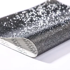 Detailed macro view of black self-adhesive rhinestone sticker sheet with backing paper