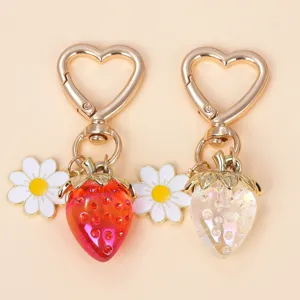 Close-up of sweet translucent strawberry and daisy flower heart-shaped keychains