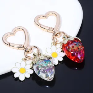 Detail of translucent strawberry and daisy heart-shaped keychains for bag decoration.