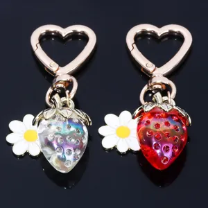 Macro detail of translucent strawberry keychains with daisy charms and heart-shaped clasps.