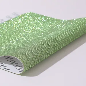 Close-up of light green rhinestone adhesive sheet showing glitter texture and backing