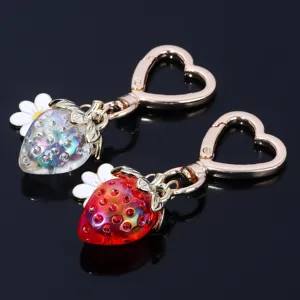 Close-up of translucent strawberry keychains with heart-shaped clasps and daisy charms