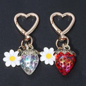 Detailed view of translucent red and iridescent strawberry keychains with daisy charms