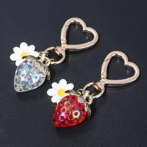 Detailed view of red and iridescent strawberry keychains with heart clasps and daisy charms