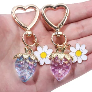 Detail view of translucent strawberry and daisy charms on heart-shaped gold keychains