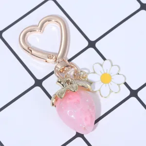 Close-up of pink translucent strawberry and daisy keychain with heart-shaped clip.