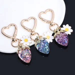 Close-up of vibrant translucent strawberry keychains with heart carabiners and daisies.