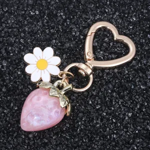 Detailed view of translucent pink strawberry keychain with daisy and heart clasp