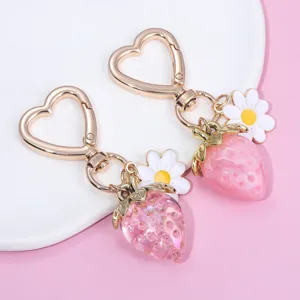 Close-up of translucent pink strawberry and daisy charms on heart-shaped keychain