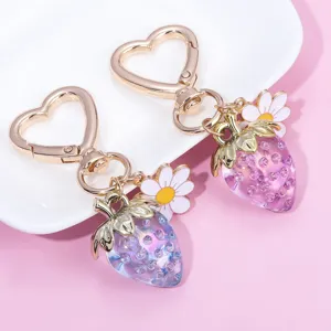 Detail view of translucent strawberry and flower charms on a heart-shaped keychain
