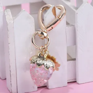 Detailed view of sweet translucent pink strawberry keychain with golden heart clasp