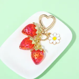 Detail of translucent red strawberry charms and white daisy on heart-shaped clasp