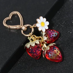Detailed close-up view of a sweet strawberry and daisy flower keychain with heart-shaped clip.