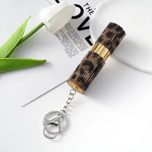 Detalle de un atomizador de perfume de leopardo con pedrería y llavero dorado chic.