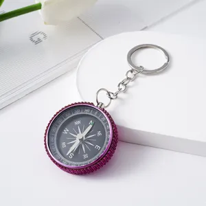 Close-up detail of a purple rhinestone-encrusted mini compass keychain for outdoor use