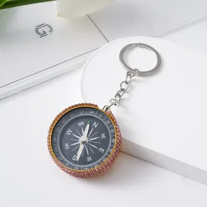 Close-up of a rhinestone-studded mini aluminum compass keychain in a gift setting