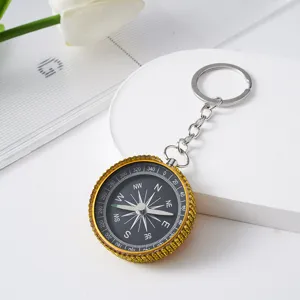 Detailed close-up view of a gold rhinestone-studded compass keychain for outdoor navigation
