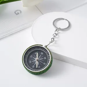 Detail of green rhinestone-studded aluminum alloy mini compass keychain on white background.