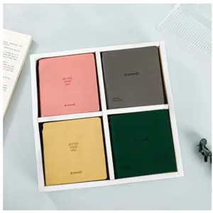 Detailed shot of pocket-sized square notebooks in four assorted pastel colors neatly arranged.