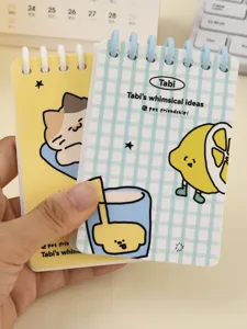 Close-up of cute A7 loose-leaf spiral notebooks with whimsical cat and lemon designs