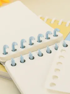 Close-up macro detail of blue detachable 7-hole plastic rings on a mini A7 loose-leaf notebook.