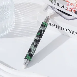 Detail view of a dual-ended rhinestone dotting pen with green camouflage pattern for nail art
