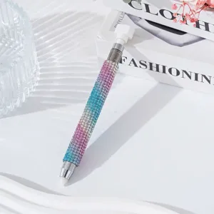 Macro detail of a double-ended rhinestone nail dotting pen with a pink-blue-purple gradient.