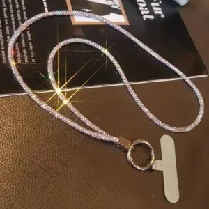 Nahaufnahme eines luxuriösen Handy-Lanyards mit Strasssteinen und Metalleinsatz
