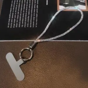 Detailansicht einer luxuriösen Handy-Handschlaufe mit silbernen Strasssteinen und Inlay.