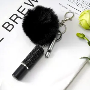 Vue détaillée du porte-clés pompon noir avec flacon de parfum en strass et sifflet métallique