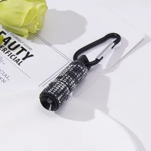 Close-up of mini LED flashlight keychain with sparkling rhinestones and carabiner.
