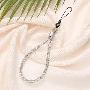 Detailed view of luxury rhinestone phone wrist strap on soft fabric background