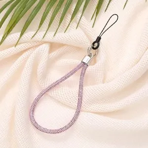 Close-up of pink 6mm rhinestone phone lanyard strap on soft beige fabric