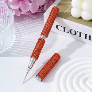 Detailed view of orange rhinestone dual-ended nail art dotting pen and liner brush