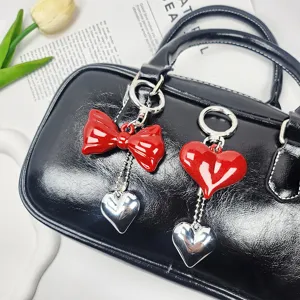Close-up of red heart and bow keychains hanging on a black handbag