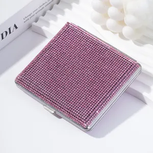 Primer plano de una pitillera de metal con pedrería rosa en un expositor blanco.