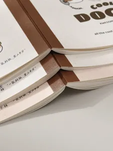 Vista detallada de tres cuadernos minimalistas en crema y marrón con encuadernación encolada