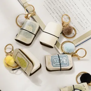 Mini notebook keychain with PU leather cover, cute fluffy pompom charm and metal ring.