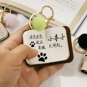 Mini PU leather notebook keychain with green pom-pom charm, cute text print and metal clasp.