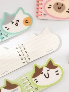 Detalle en primer plano del cuaderno de bolsillo en espiral con forma de gato con páginas rayadas.