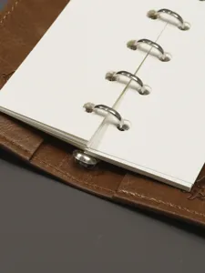 Vue détaillée d'un agenda en cuir avec anneaux métalliques et pages intérieures quadrillées.