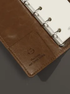 Vue détaillée d'un agenda à anneaux en cuir avec couverture chat et classeur métallique.