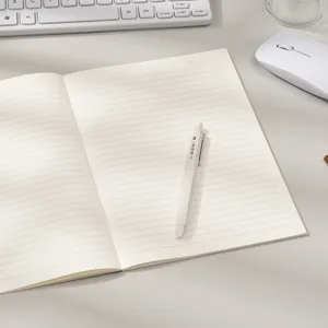 Cuaderno de líneas beige minimalista con un bolígrafo blanco en un escritorio limpio