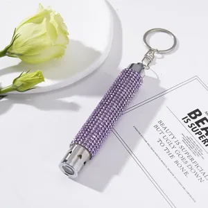 Close-up of a mini LED keychain flashlight decorated with shiny purple rhinestones