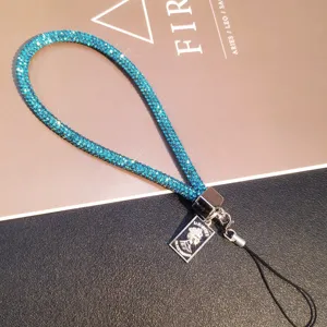 Detail showing sparkling blue rhinestone phone charm with silver portrait pendant
