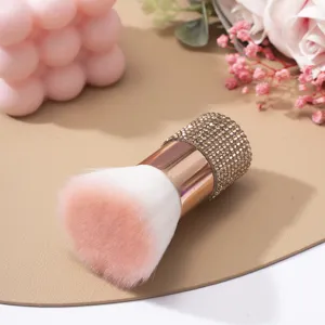 Détail macro d'un pinceau à ongles de luxe en or rose avec un manche serti de strass