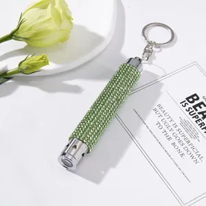 Close-up of mini LED flashlight keychain encrusted with sparkling green rhinestones.