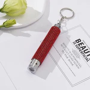 Detailed close-up of mini LED flashlight keychain with sparkling red rhinestones.