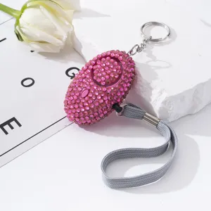 Close-up of sparkling pink rhinestone personal safety alarm with keychain and wrist strap